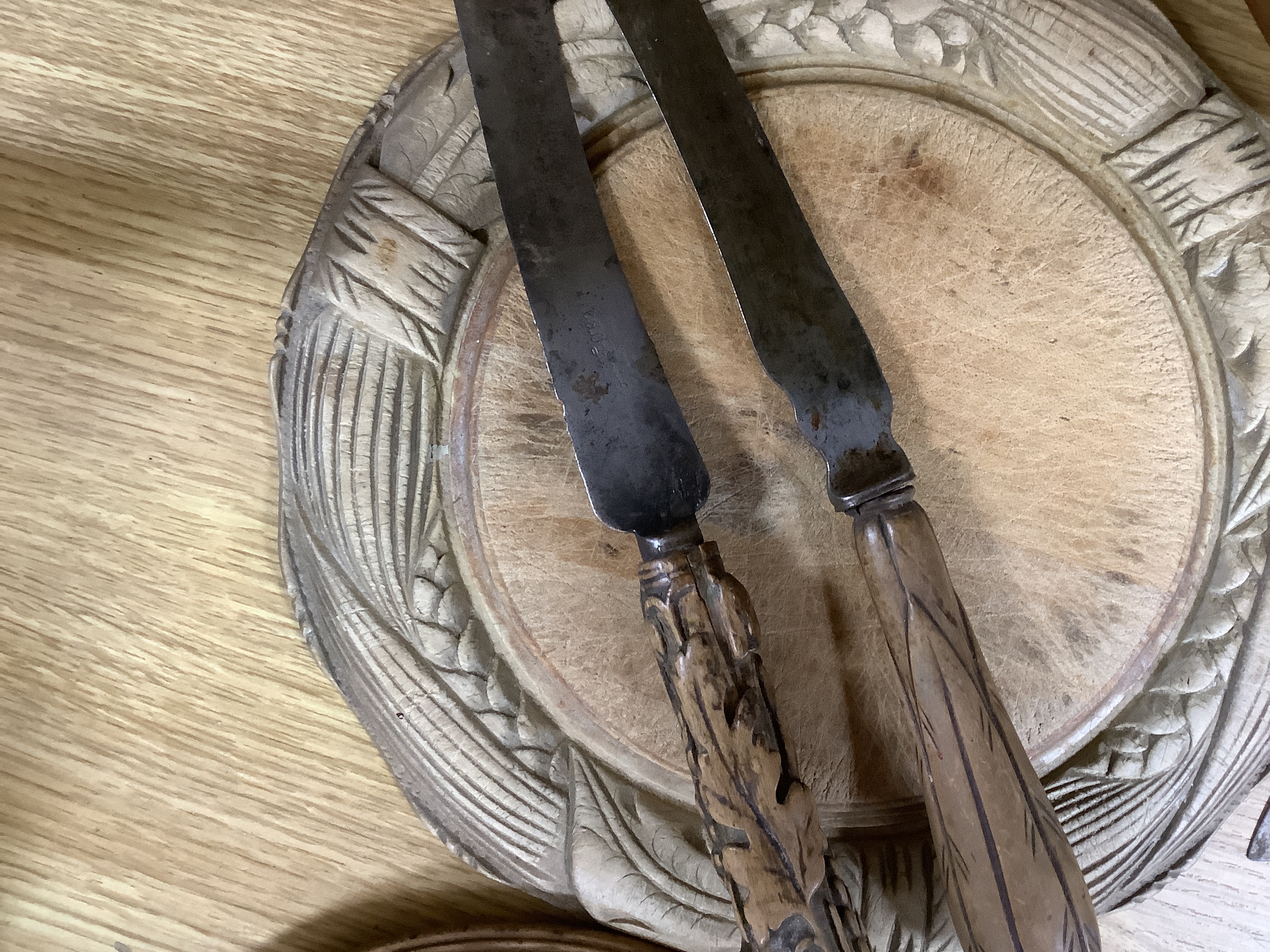 Three carved wood breadboards, a butter dish and a collection of knives with carved handles, largest 29cm in diameter